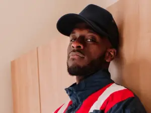 black man standing with black cap and jacket