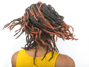 woman wearing yellow shirt playing around dreads