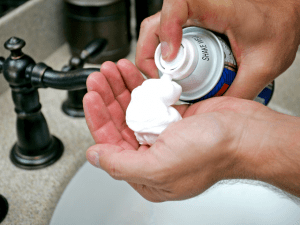 man spraying shaving cream foam in hands