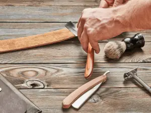 man stropping a straight razor with leather