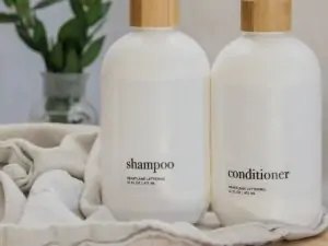 white bottles of shampoo and conditioner with a towel