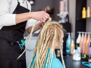 woman with hair being done into dreadlocks