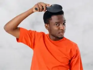 Man in orange shirt combing through hair