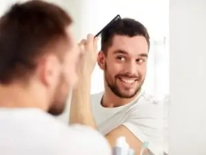 man combing his hair in front of a mirror
