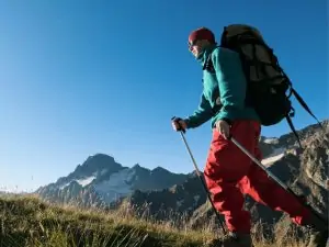 Man wearing red pants carrying a bag in mountain
