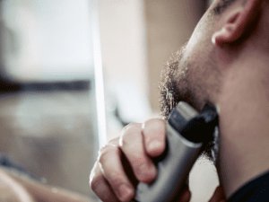 man using a shaver to trim beard