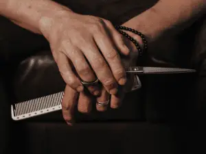 man holding a hair cutting scissor and a comb