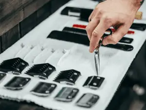 person with scissor touching hair clipper blades