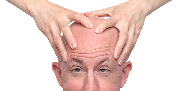 Man with a shaved head getting a massage.