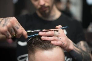 Barber trimming hair of male customer